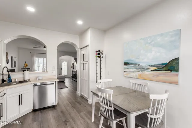 a kitchen with stainless steel appliances a dining table chairs and wooden floor