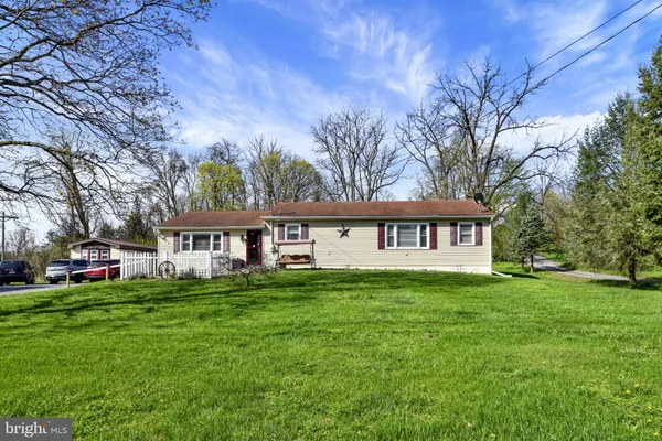 a view of a house with a big yard and large trees