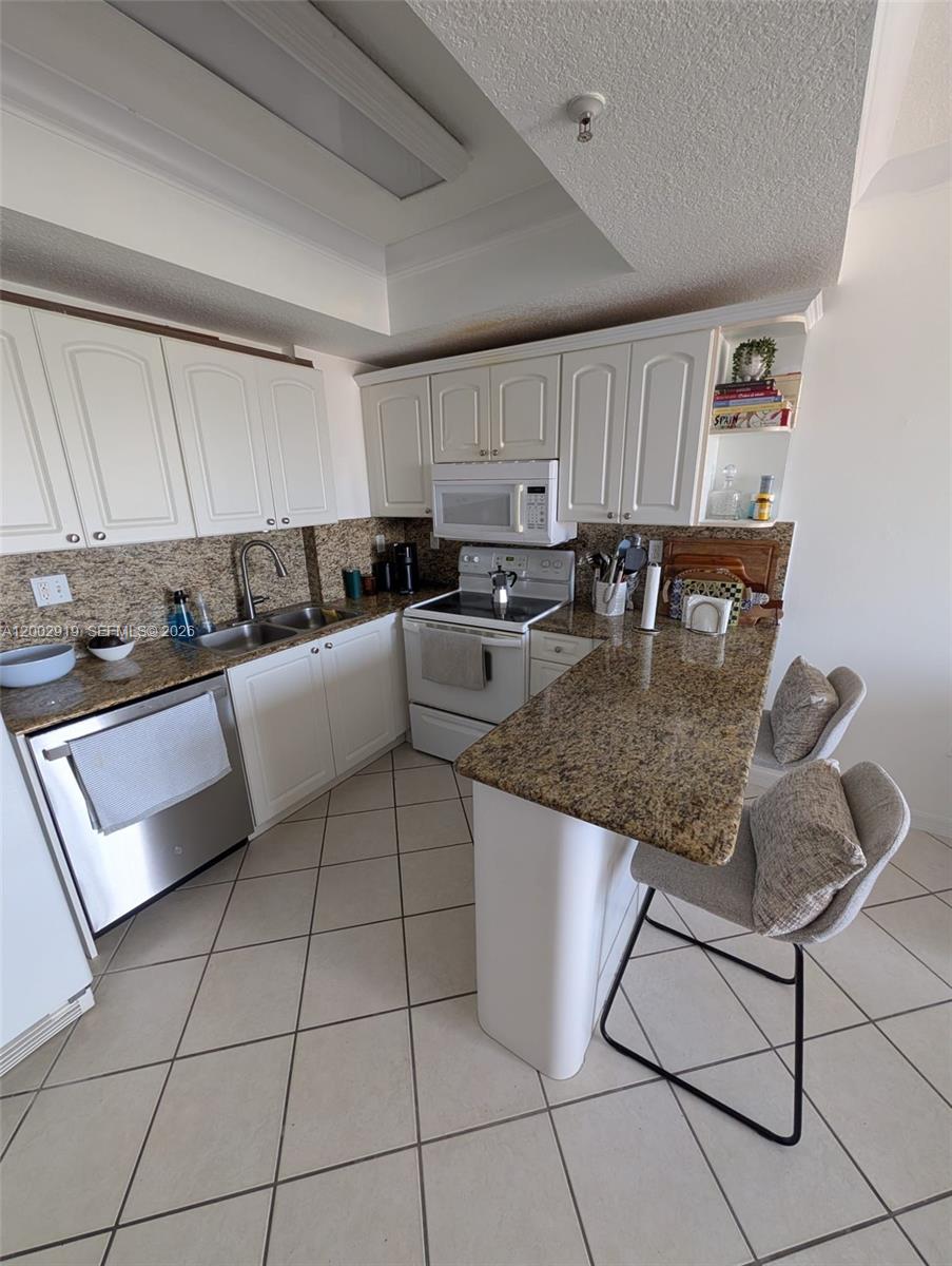 3500 Coral Way, Unit 505 Miami, FL 33145 - Photo 9 of 18 a kitchen with granite countertop a stove a sink dishwasher and a refrigerator with white cabinets