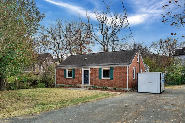 a view of a house with a yard and large tree