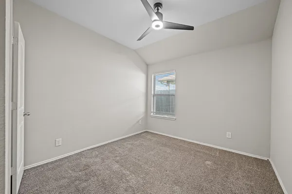 an empty room with a chandelier fan and windows