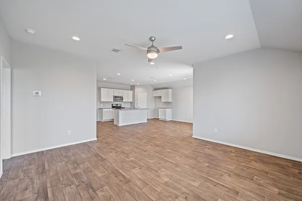 a view of kitchen and empty room with wooden floor