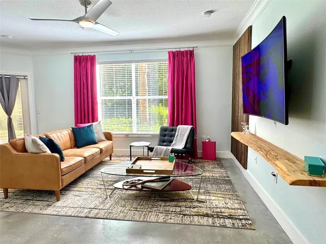 a living room with furniture a flat screen tv and a window