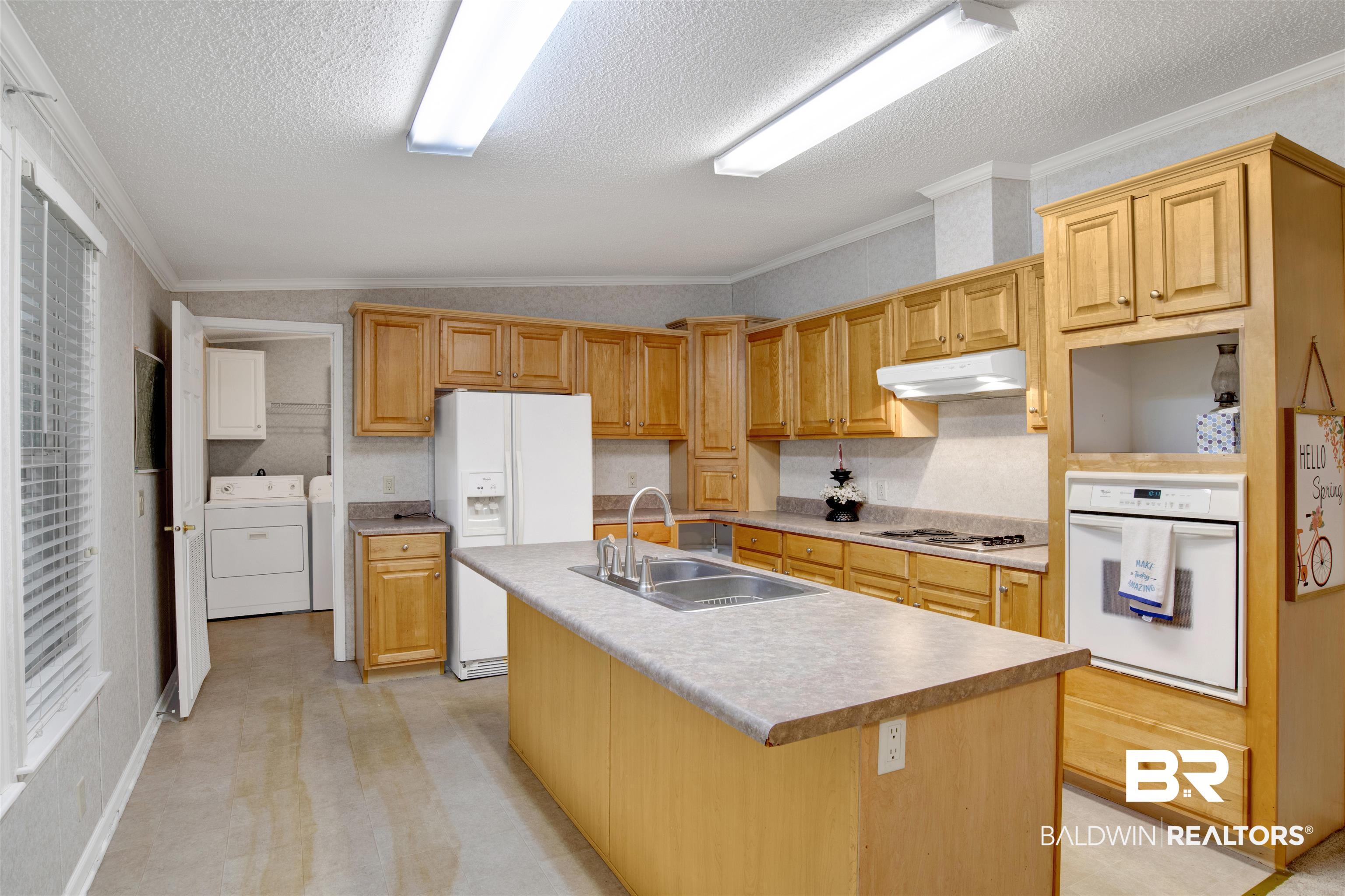25700 County Road 71 Robertsdale, AL 36567 - Photo 9 of 40 Kitchen with white appliances, washer and clothes dryer, under cabinet range hood, a textured ceiling, and an island with sink