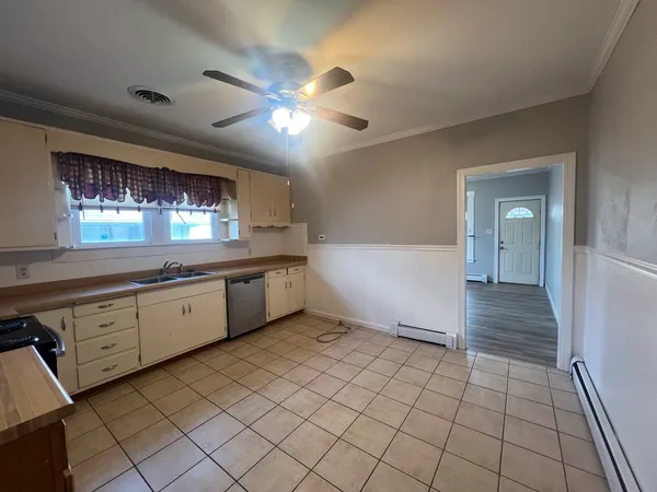 a large white kitchen with a sink window and cabinets