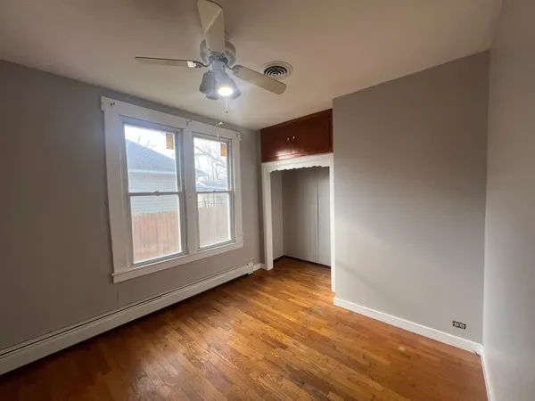 an empty room with wooden floor chandelier fan and windows