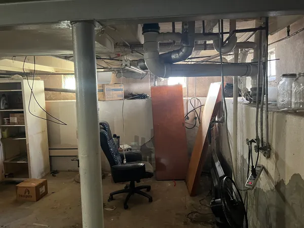 a view of a room with water heater and wooden cabinets