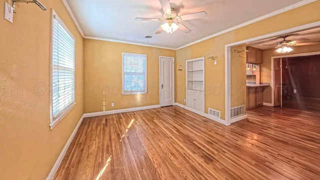 a view of an empty room with wooden floor and a window