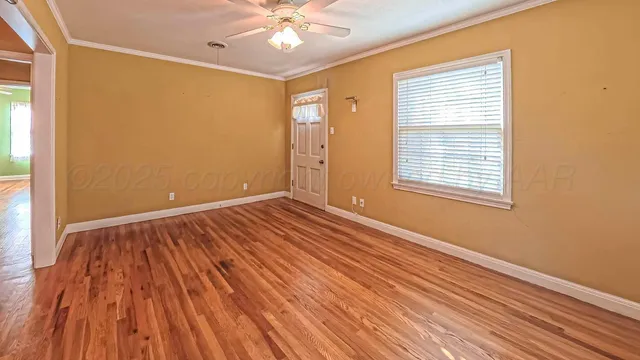 a view of an empty room with wooden floor and a window