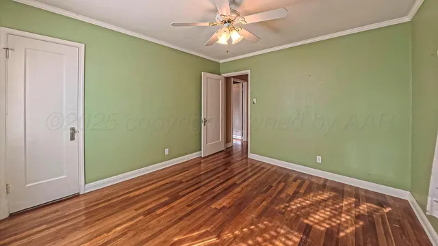 an empty room with wooden floor closet and chandelier fan