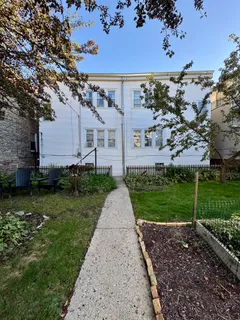 a view of a white house next to a yard with big trees