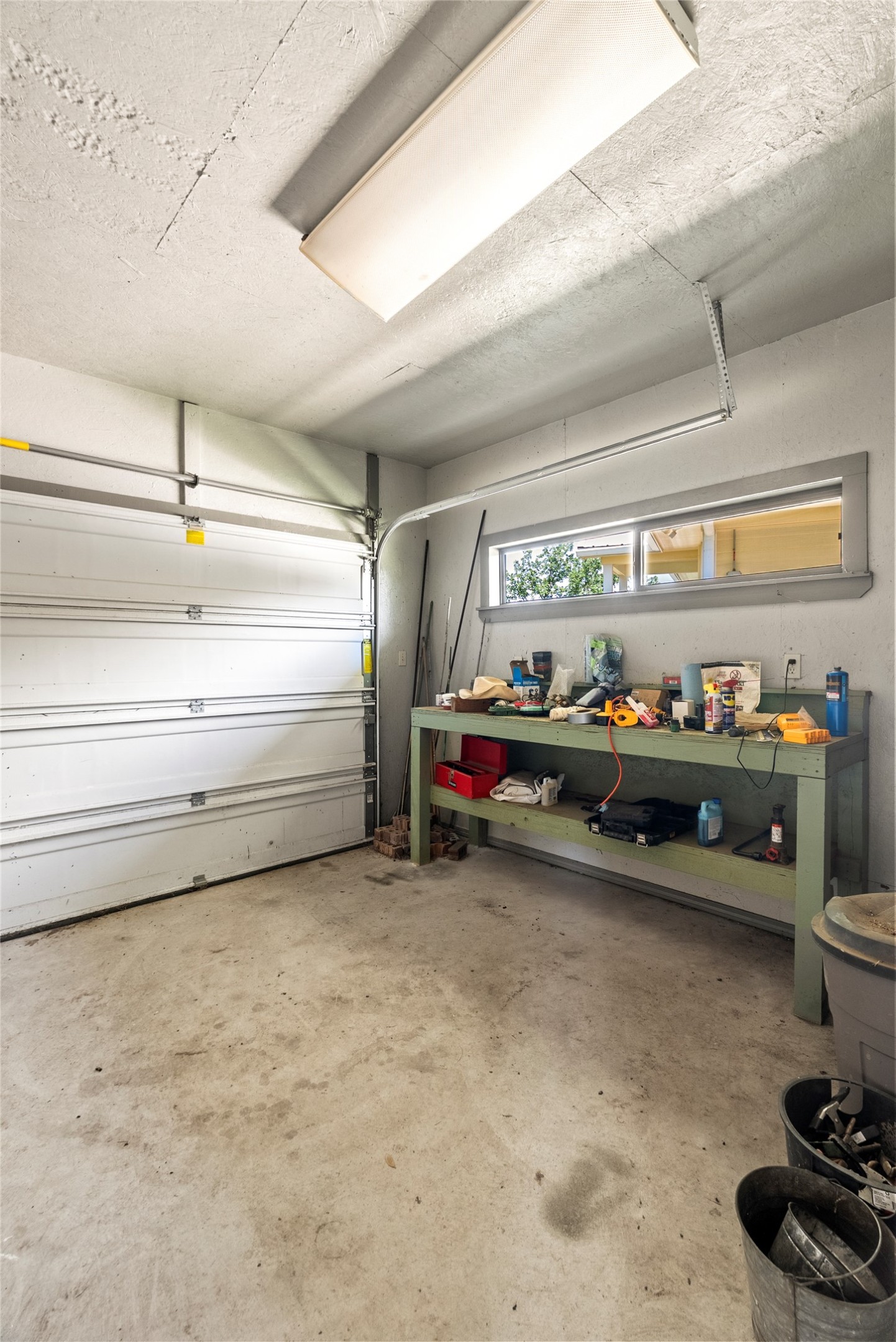 928 Upper Elgin River Road Elgin, TX 78621 - Photo 33 of 40 Garage featuring a concrete floor, built-in workbench, and overhead fluorescent lighting