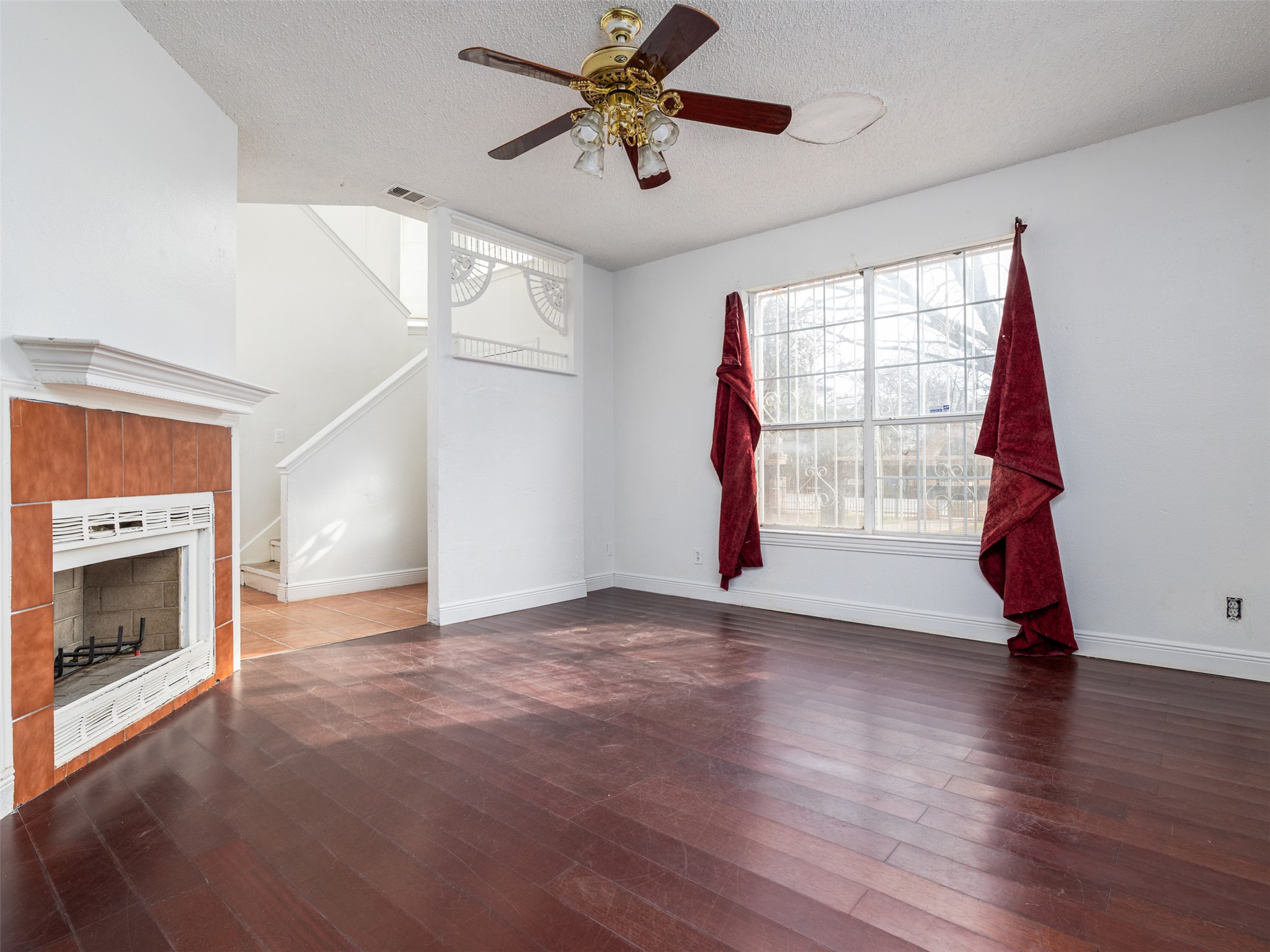 506 Tillery Street Austin, TX 78702 - Photo 3 of 12 Unfurnished living room featuring a ceiling fan, a tile fireplace, dark wood-style flooring, and a textured ceiling