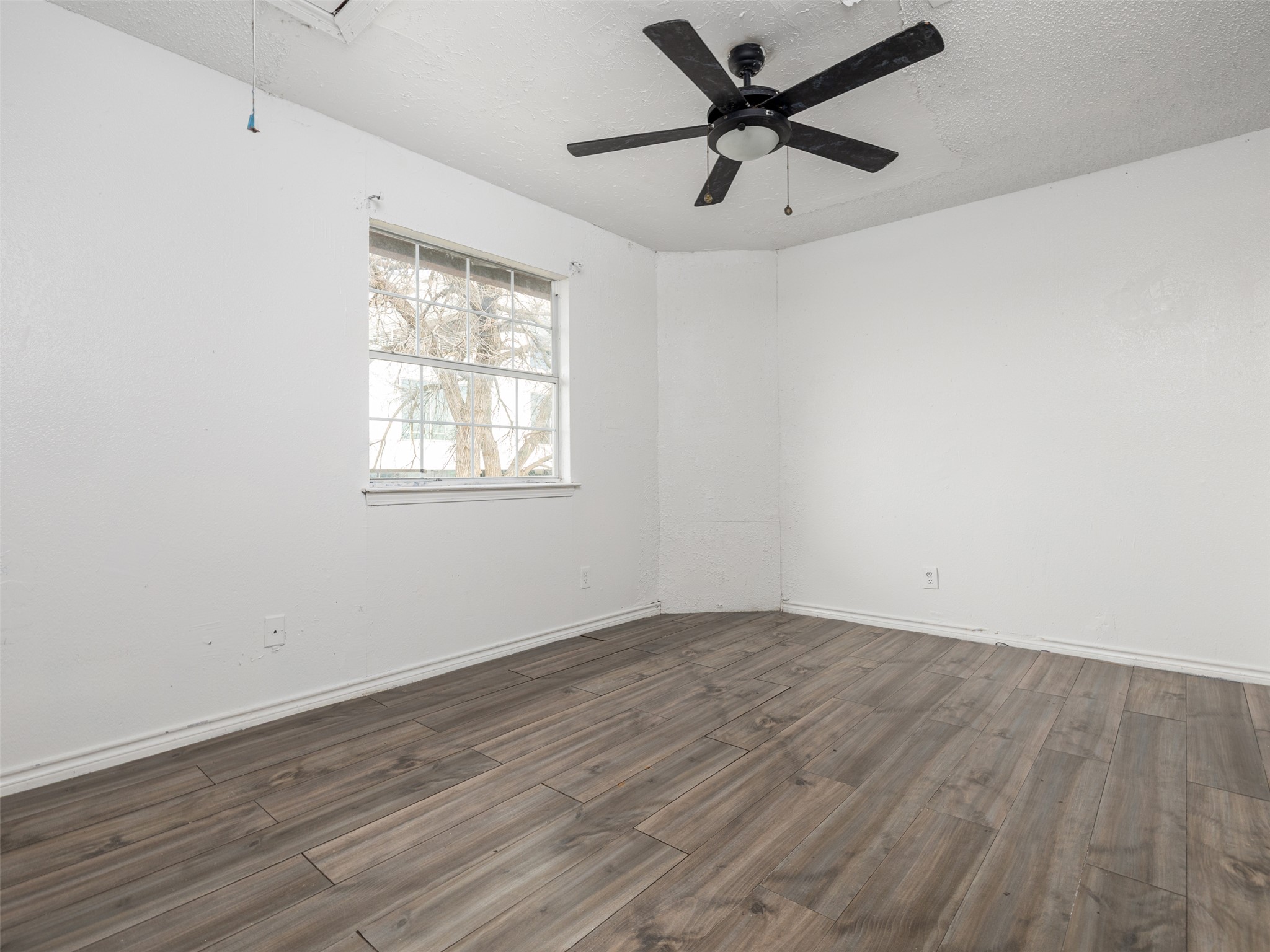 506 Tillery Street Austin, TX 78702 - Photo 8 of 12 Spare room featuring dark wood-type flooring, a ceiling fan, and a textured ceiling