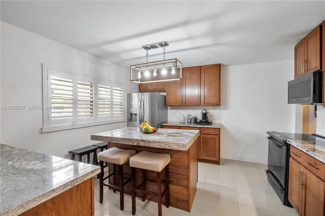 a kitchen with stainless steel appliances granite countertop wooden cabinets a stove a sink and a refrigerator