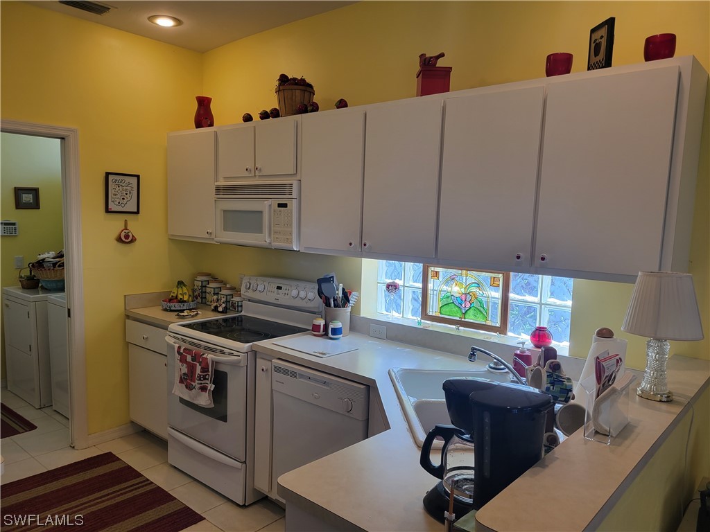 10720 Blue Bimini Circle Estero, FL 33928 - Photo 7 of 28 a kitchen with stainless steel appliances a white stove top oven a sink a dining table and chairs with wooden floors