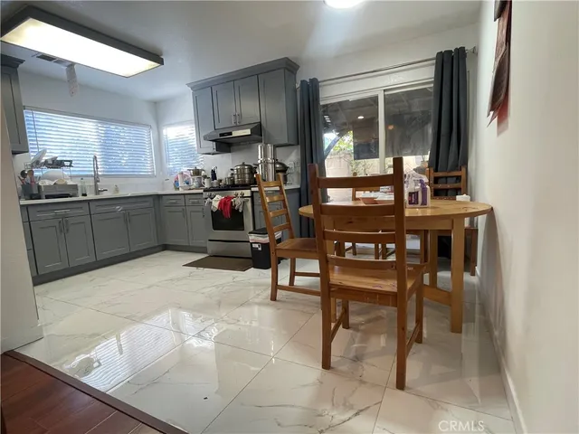 a kitchen with stainless steel appliances kitchen island granite countertop dining table chairs and a large window