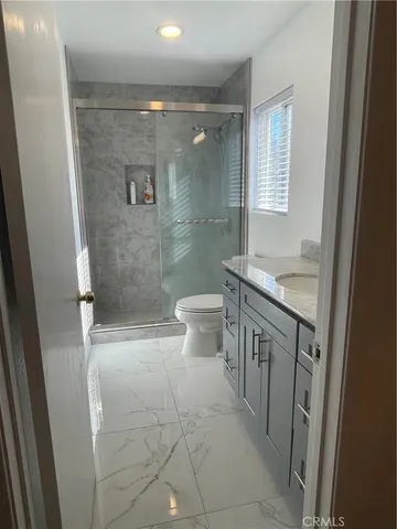 a bathroom with a granite countertop sink a toilet and a shower