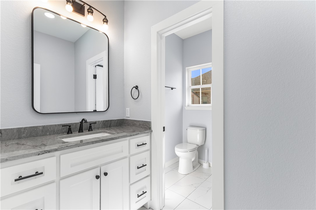 308 Crye Circle Winters, TX 79567 - Photo 36 of 44 a bathroom with a granite countertop toilet sink and mirror