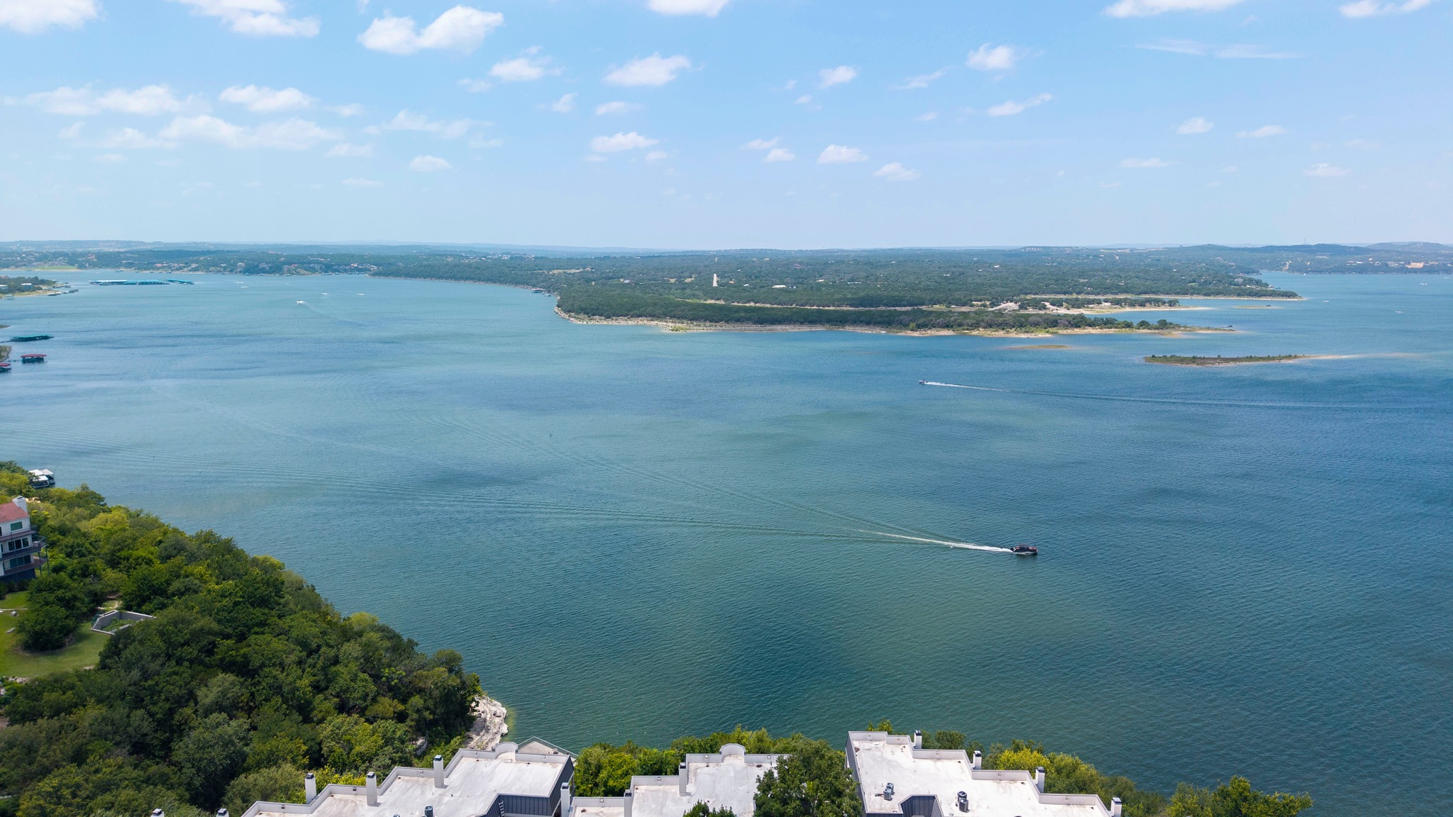 A boat streaks across the expansive lake, framed by distant shores and lush greenery.