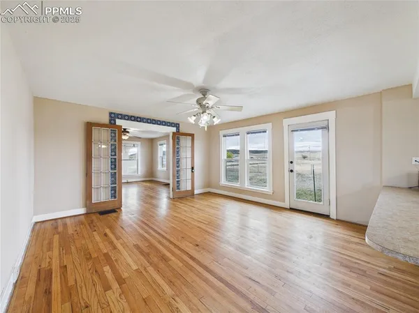 a view of an empty room with wooden floor and a window