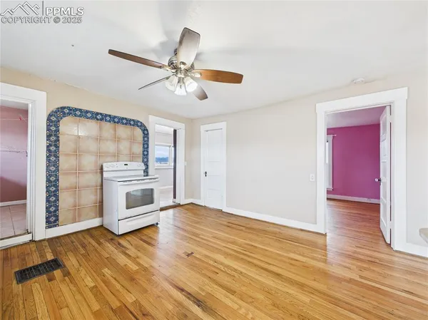 a view of a livingroom with a fireplace a ceiling fan and wooden floor