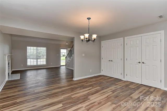 a view of a room with wooden floor and a chandelier