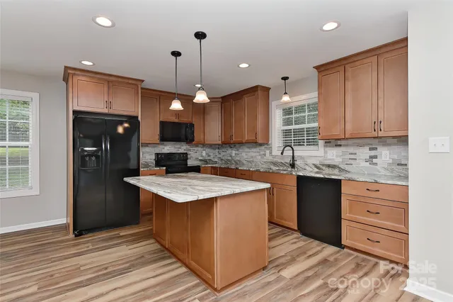 a large kitchen with granite countertop a large counter top a sink stainless steel appliances and cabinets