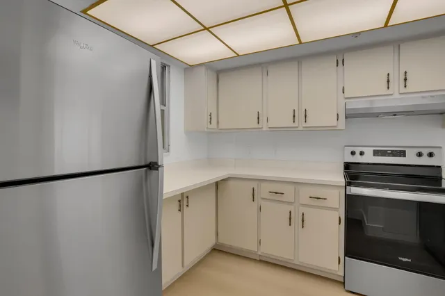a kitchen with white cabinets and white stainless steel appliances and a refrigerator