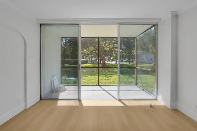 a view of an empty room with wooden floor and windows