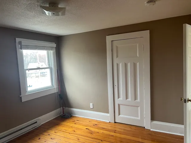 an empty room with wooden floor closet and windows