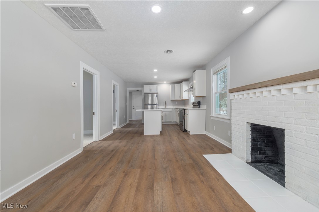 218 Roxboro Road Vermilion, OH 44089 - Photo 10 of 50 Unfurnished living room featuring dark wood-style floors, a fireplace, and recessed lighting