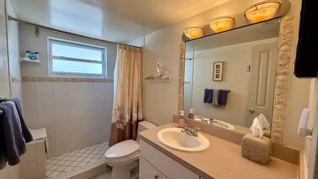 a bathroom with a granite countertop toilet a sink and a mirror