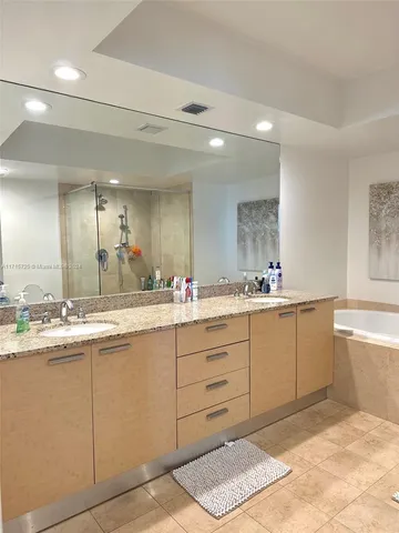a bathroom with a sink vanity granite tub shower and a mirror