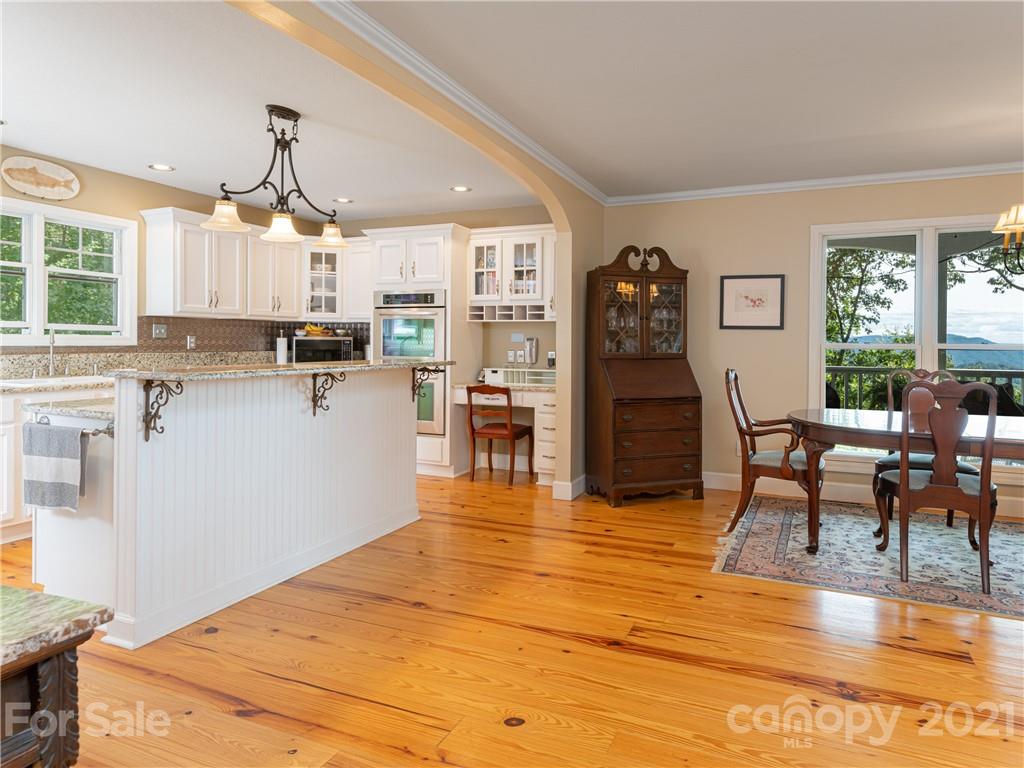 10 Powder Ridge Drive Asheville, NC 28803 - Photo 16 of 46 a kitchen with stainless steel appliances kitchen island granite countertop a refrigerator a stove top oven a dining table and chairs with wooden floor
