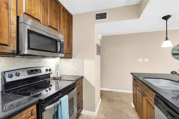 a kitchen with stainless steel appliances a stove a microwave a sink and cabinets