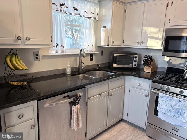 a kitchen with granite countertop a sink a stove and cabinets