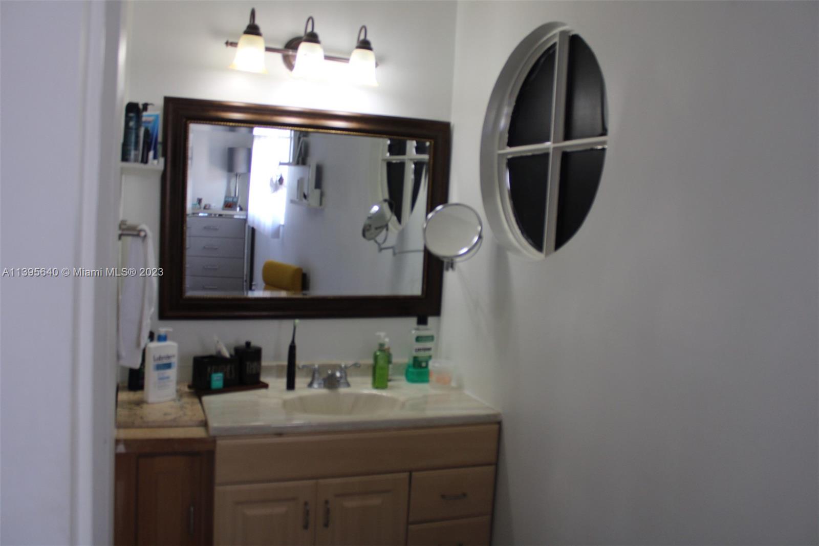 13475 Southwest 62nd Street, Unit 5 Miami, FL 33183 - Photo 29 of 32 a bathroom with a sink and mirror