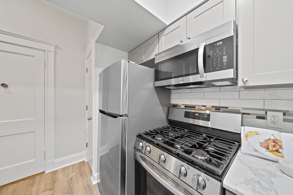 1564 Commonwealth Avenue, Unit 3 Boston, MA 02135 - Photo 5 of 9 a kitchen with stainless steel appliances granite countertop a stove and a refrigerator