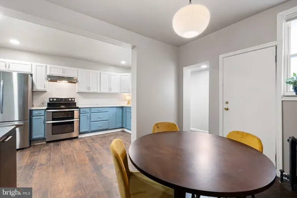 a kitchen with stainless steel appliances a dining table chairs and refrigerator