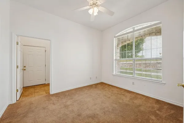 an empty room with a window and a chandelier fan