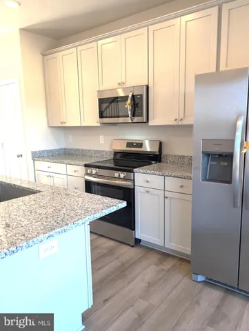 a kitchen with stainless steel appliances granite countertop a stove a sink and white cabinets