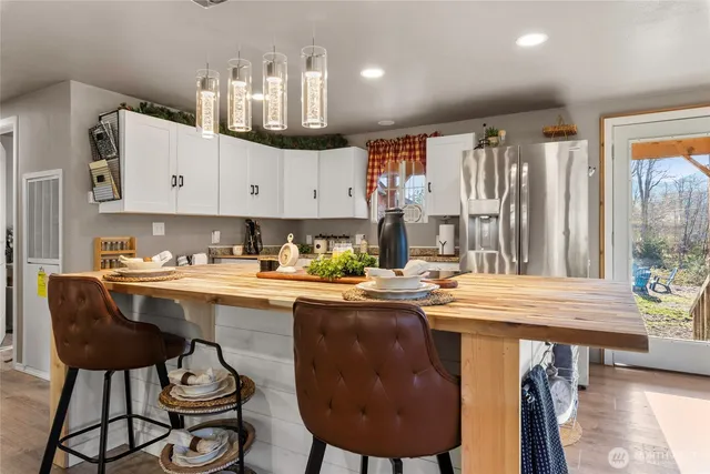 a kitchen with stainless steel appliances granite countertop a sink a stove a window and chairs