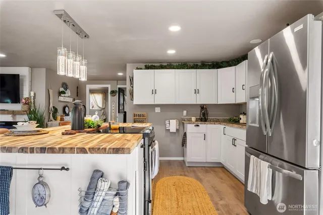 a kitchen with stainless steel appliances granite countertop a refrigerator a sink and white cabinets