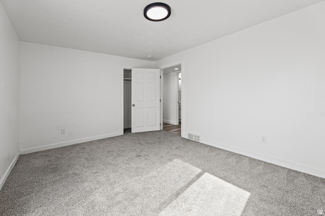5525 Hampton Way Stansbury Park, UT 84074 - Photo 28 of 35 Spacious interior room with light gray carpet, white painted walls, and a contemporary flush-mount ceiling light