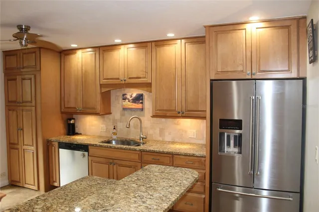 a kitchen with stainless steel appliances granite countertop a refrigerator and a sink