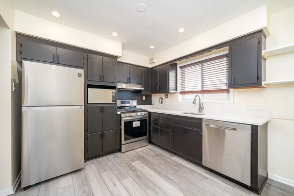 a kitchen with a refrigerator a sink a stove a microwave and wooden cabinets