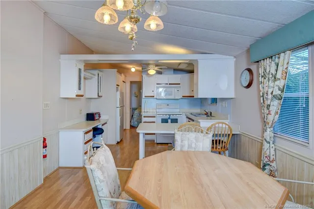 a kitchen with stainless steel appliances granite countertop a sink dishwasher a stove a dining table and chairs with wooden floor