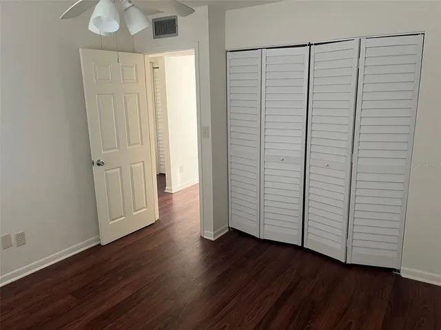 an empty room with wooden floor & closet area