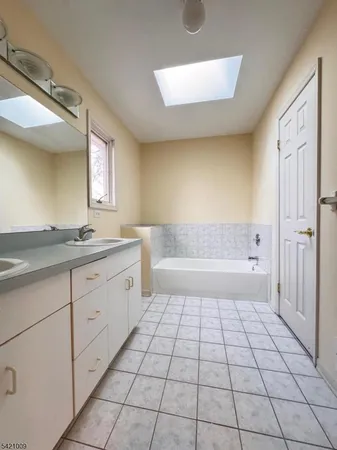 a spacious bathroom with a granite countertop sink a mirror and a bathtub